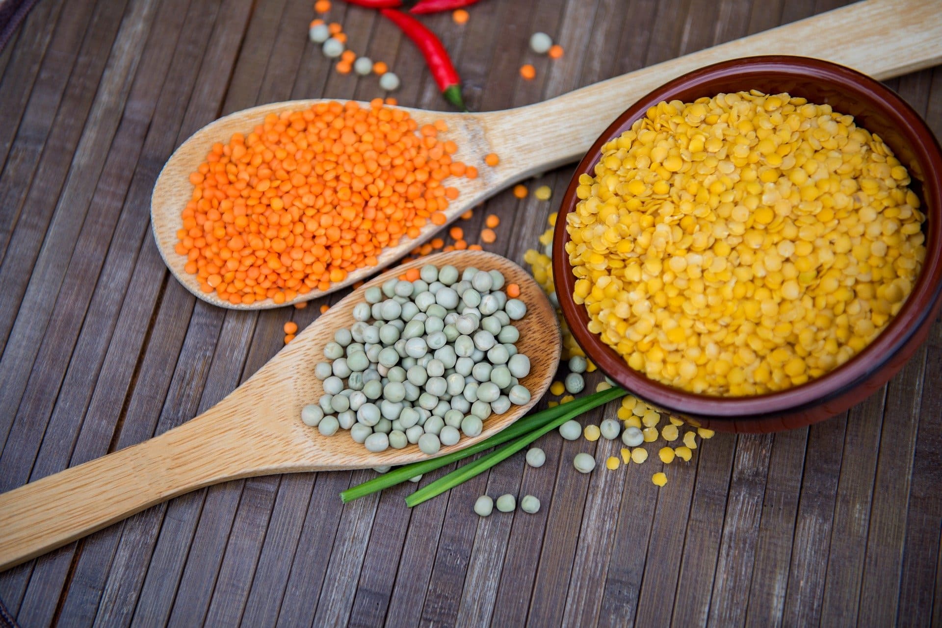 multi-colored lentils in serving spoons and bowl