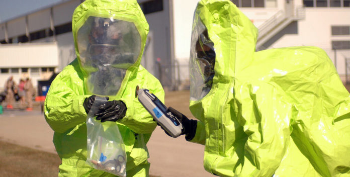 Personas en trajes HAZMAT desechando productos químicos domésticos