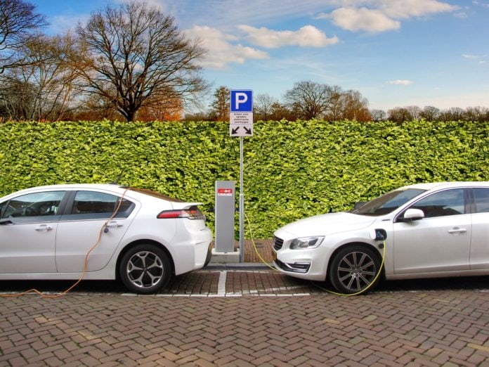 Two white electric cars charging at a charging station