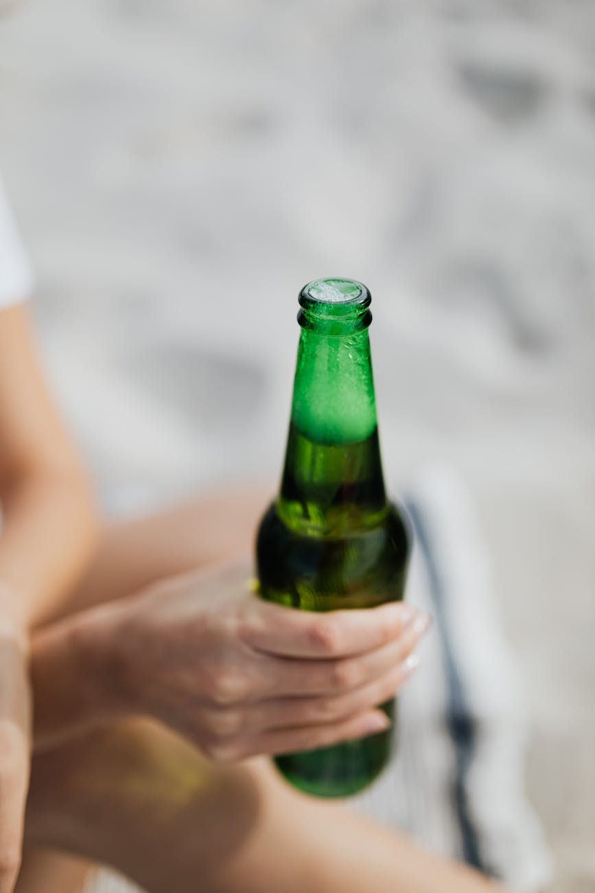person holding a green glass bottle of beer