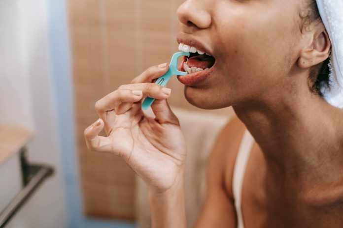 ethnic woman cleaning teeth with dental floss