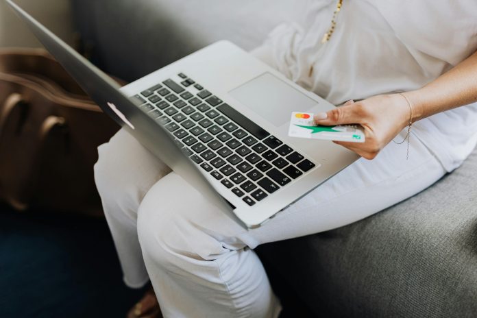 person holding credit card and laptop