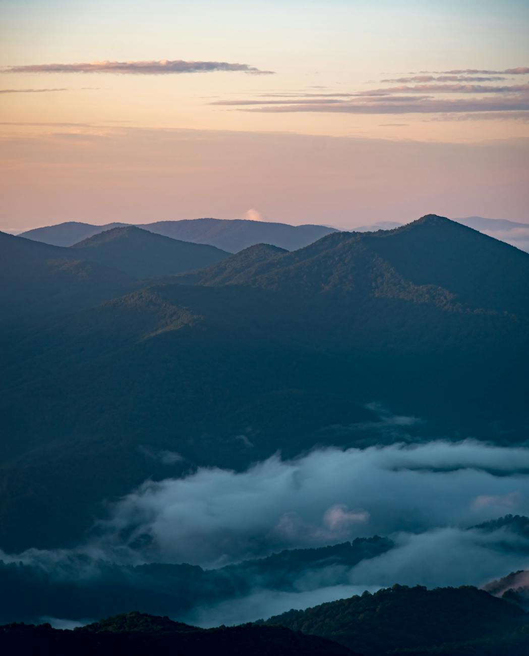 the sun rises over the mountains and clouds