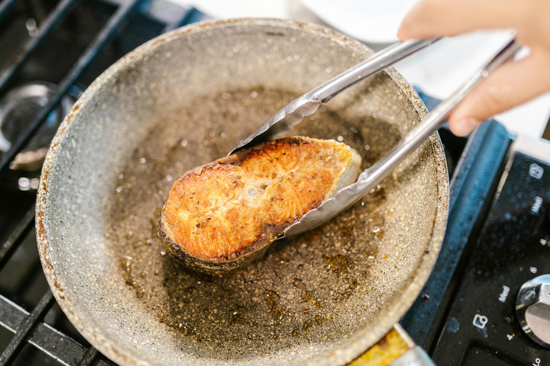 holding fish meat on pan with pincers